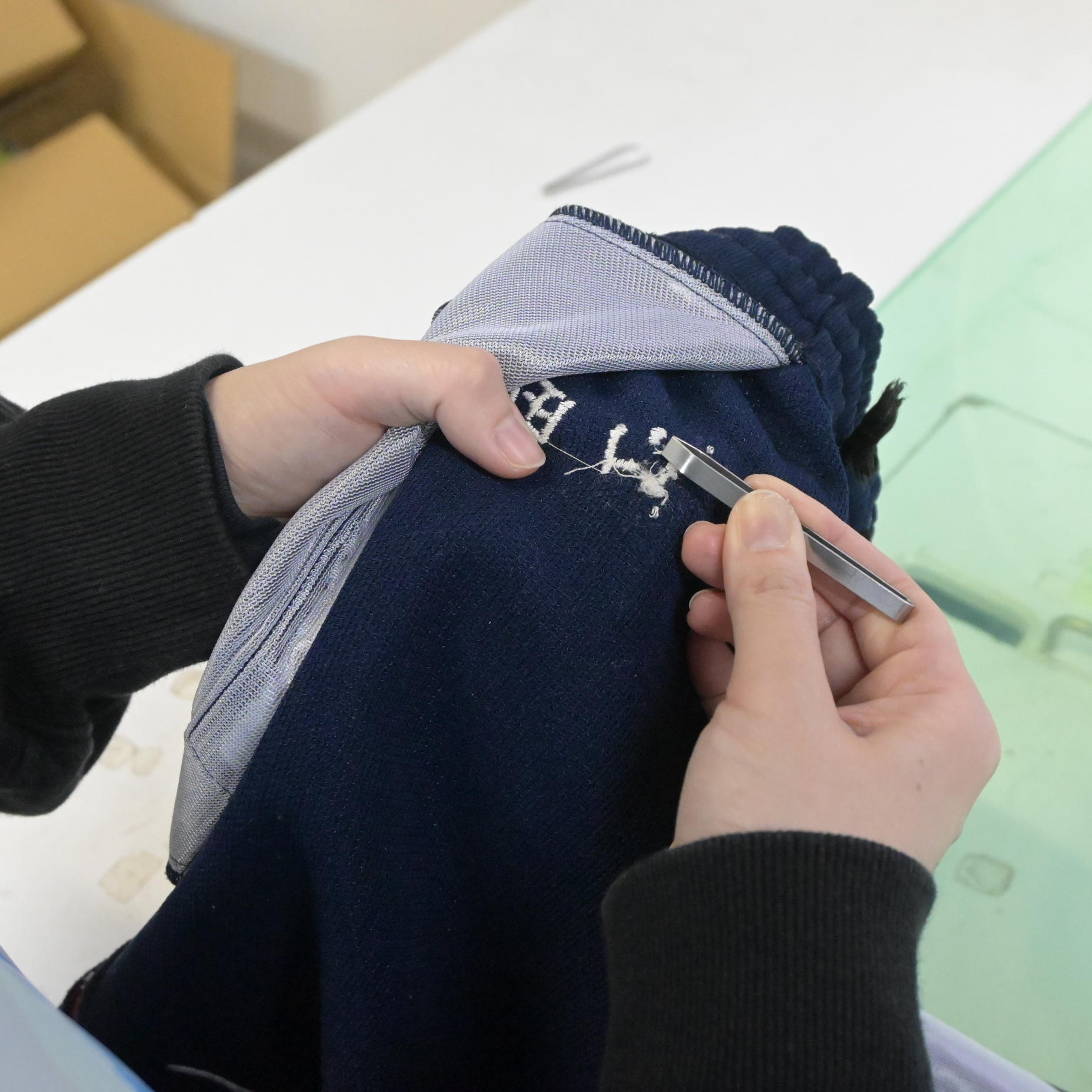 ピンセットで刺繍糸を1本ずつ丁寧につかんで引き抜いている