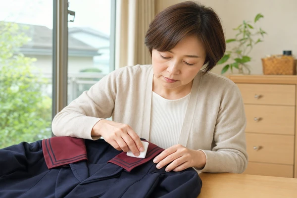 北陸学院制服のセーラー衿まわりを布で丁寧にお手入れする母親