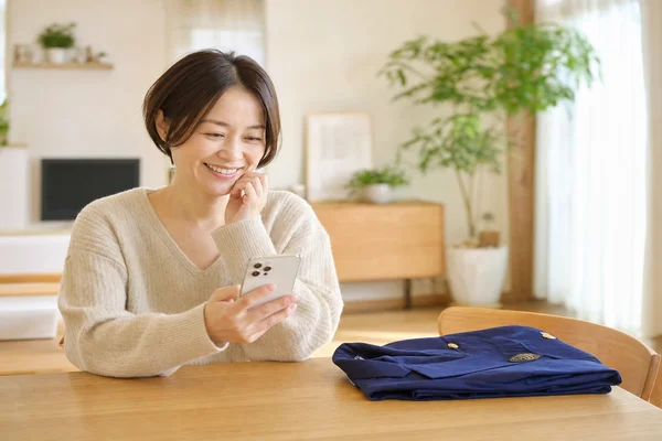茨城キリスト教学園の制服売却後にスマートフォンで査定結果を確認して満足そうに微笑むお母さんの写真