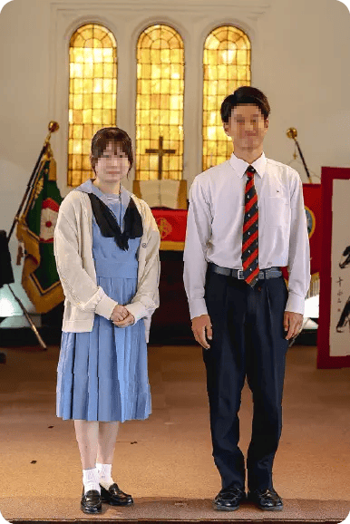 ルーテル学院高等学校の夏服制服。女子は水色のセーラー服に黒のネクタイと白カーディガン、男子は白ワイシャツに赤黒ストライプのネクタイを着用している。背景はルーテル学院のチャペル。
