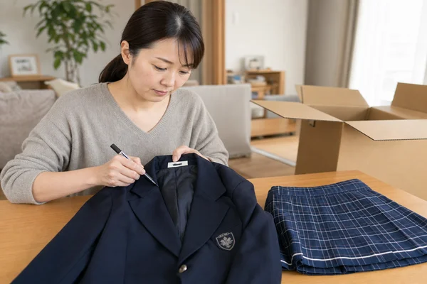 買取査定に出す前に制服のネームタグをマーカーで塗りつぶす様子