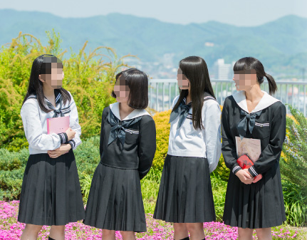 足利大学附属女子高等学校の制服（セーラー服・黒スカート）を着た生徒が屋外に集まっている様子