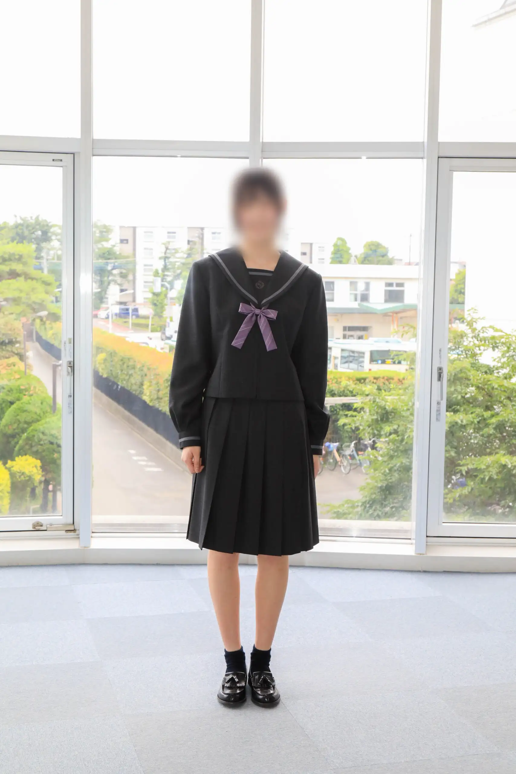 文華女子高等学校（東京文華高等学校）の女子冬服。黒を基調にグレーのラインが入った長袖セーラー服、パープル系のリボン、黒のプリーツスカートのコーディネート