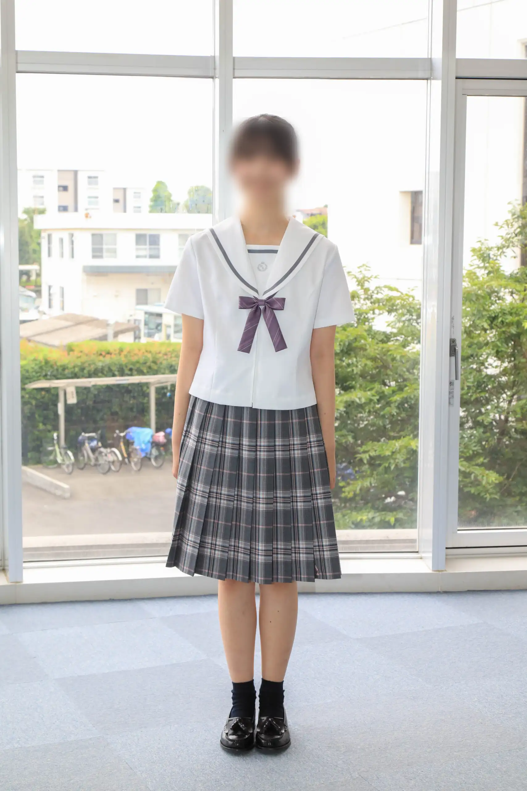 文華女子高等学校（東京文華高等学校）の女子夏服。白の半袖セーラーブラウスにグレーラインのセーラー襟、パープル系のリボン、グレー基調のチェック柄プリーツスカートを合わせた夏のコーディネート