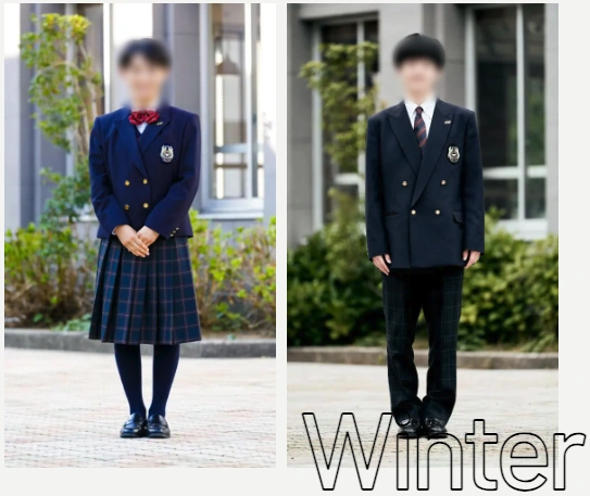 福井工業大学附属福井高等学校の冬服を着用した女子・男子生徒。男女ともに紺色のダブルブレザーに校章エンブレム、女子は赤リボン＋紺系チェック柄プリーツスカート、男子はストライプネクタイ＋紺系チェック柄スラックスを合わせている