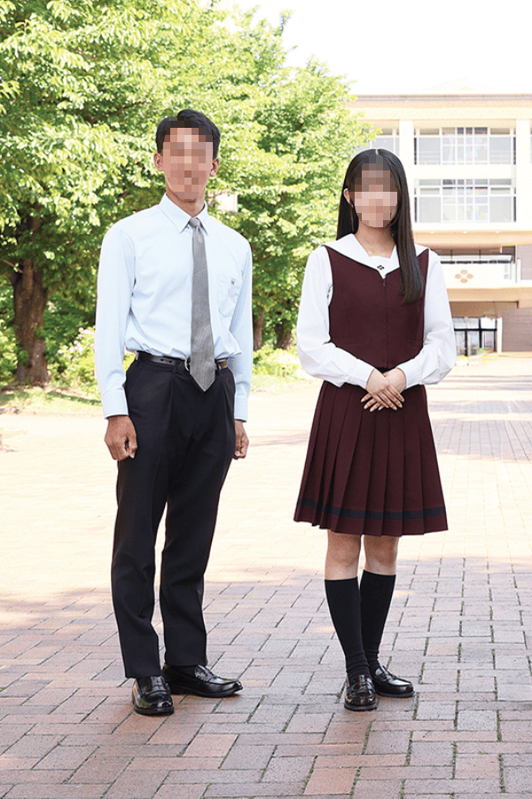 共愛学園高等学校の夏服を着用した男女生徒。女子は白ブラウスにボルドーベストとプリーツスカート、男子は白シャツにネクタイとスラックス
