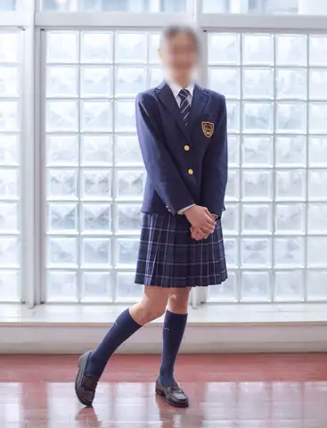 品川エトワール女子高等学校の冬服。胸にエンブレムが入った濃紺ブレザーとブルーチェックのスカート、ネクタイ、紺ハイソックスのコーディネート