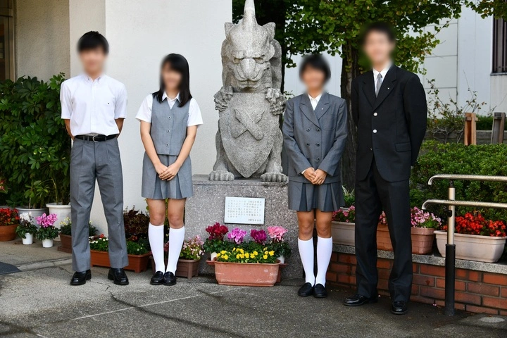 慶應義塾中等部の従来タイプの基準服（3年生）を着用した生徒。夏服の白シャツとグレースラックス、女子のベスト・ジャケットスタイル、冬服のダークスーツ