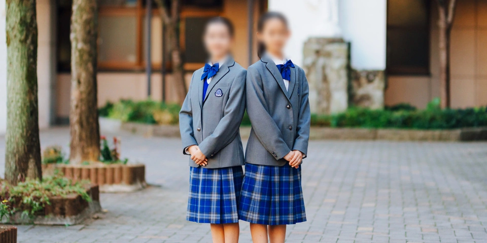 熊本信愛女学院中学校の冬服を着た生徒。グレーのブレザーとブルーチェックのスカート