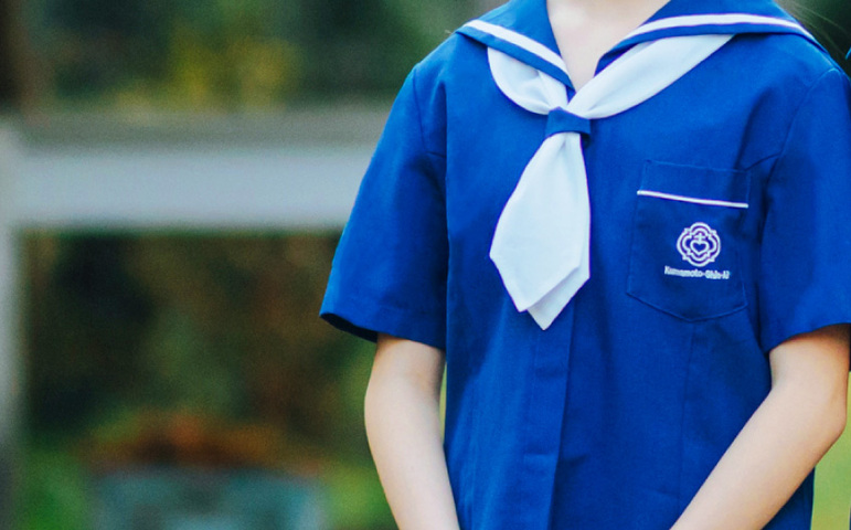 熊本信愛女学院中学校の夏服の胸元。白いセーラーカラーとタイ、胸ポケットの校章刺繍が入った青い夏服