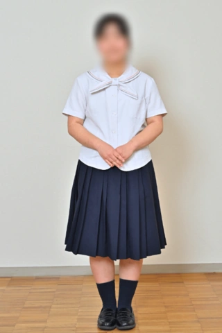 京都聖母学院中学校の夏服。セーラー襟の白い半袖ブラウスに濃紺のプリーツスカートを合わせた女子生徒