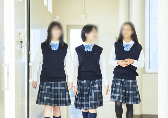 聖カピタニオ女子高等学校の冬服。白ブラウスに紺のベスト、水色のリボン、チェックのプリーツスカート、紺のタイツを着用した女子生徒